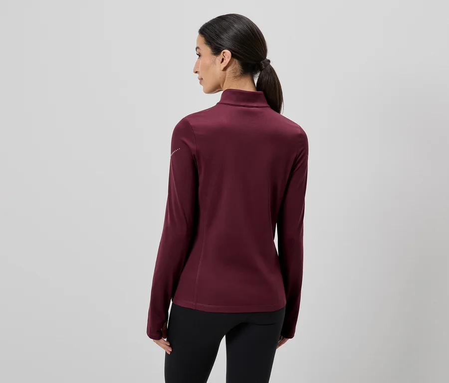 Vue arrière d'une femme portant un haut bordeaux à manches longues et un pantalon noir, les cheveux attachés en queue de cheval.