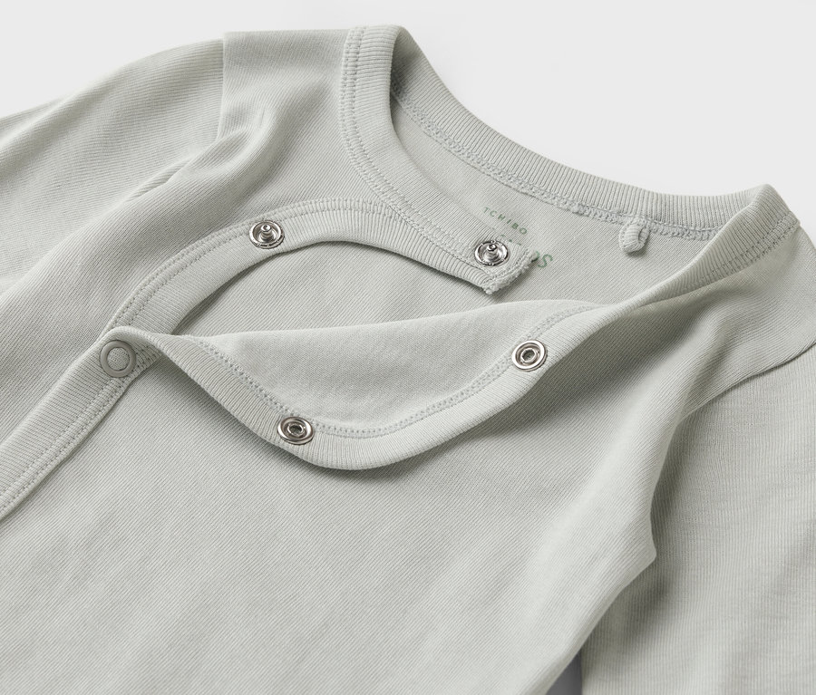 Gros plan sur un body bébé bleu-gris clair à manches longues avec boutons-pression.