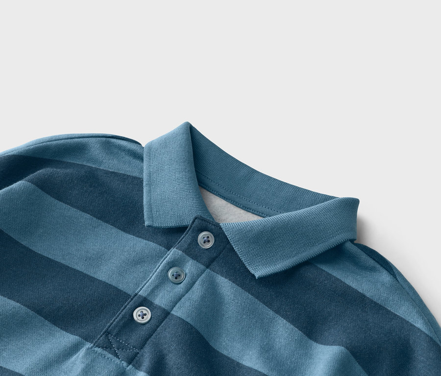 Gros plan d'un polo bleu rayé avec trois boutons au niveau du col.