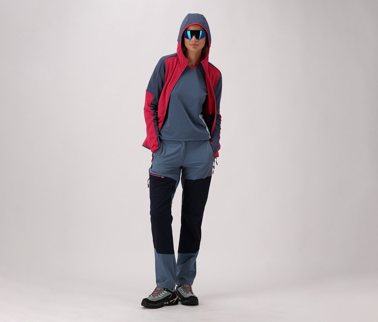 Femme portant des lunettes de soleil et une veste à capuche posant avec des chaussures de trekking vertes CMP Rigel Low 2.0 WP.