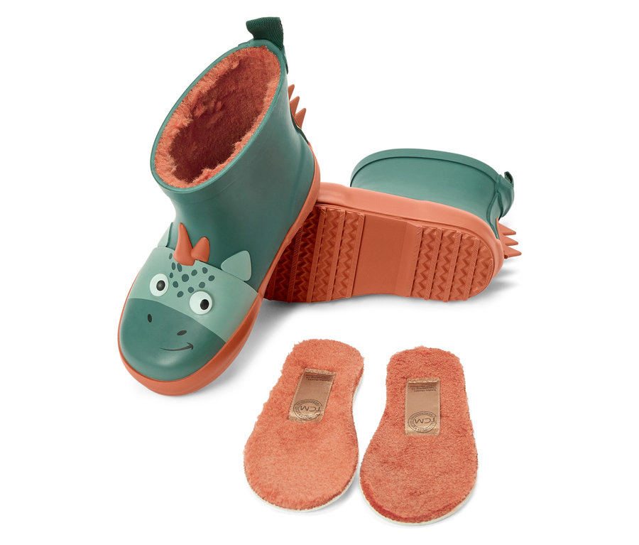 Deux bottes en caoutchouc vertes pour enfants avec un visage de dinosaure et une semelle orange, à côté de deux semelles intérieures orange.