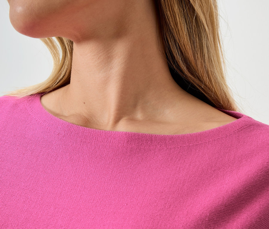 Gros plan d'une femme aux cheveux blonds portant un pull rose.