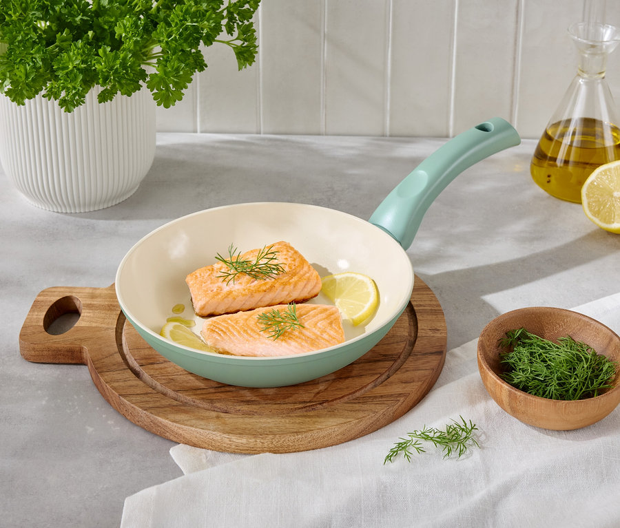 Deux filets de saumon avec des tranches de citron et de l'aneth dans une poêle claire sur une planche à découper en bois.