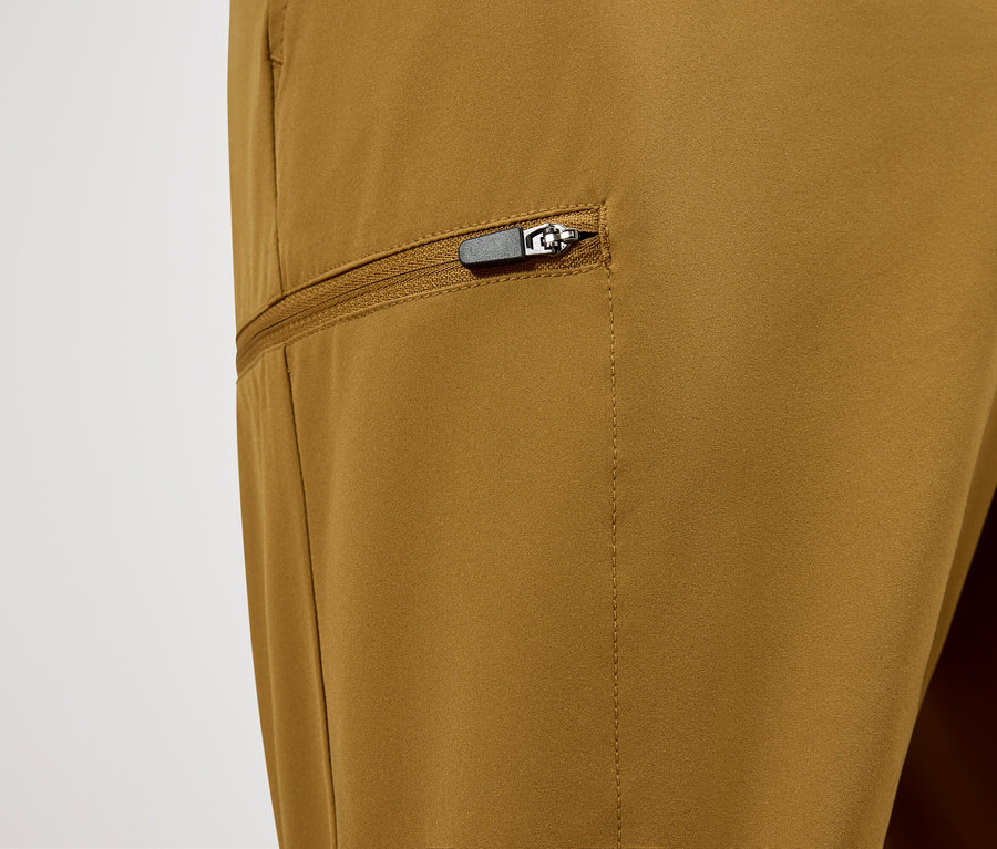 Gros plan d'un pantalon ocre avec une poche zippée.