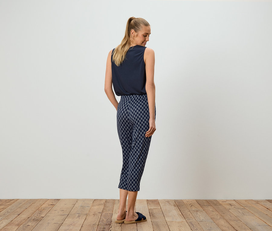 Femme portant un haut bleu et un pantalon à motifs, vue de dos.