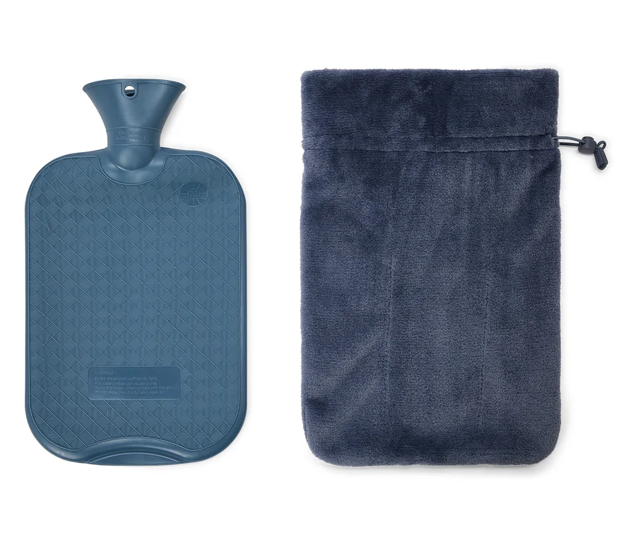 Une bouillotte bleue à motif losanges est posée à côté d'un sac en velours bleu avec cordon de serrage.