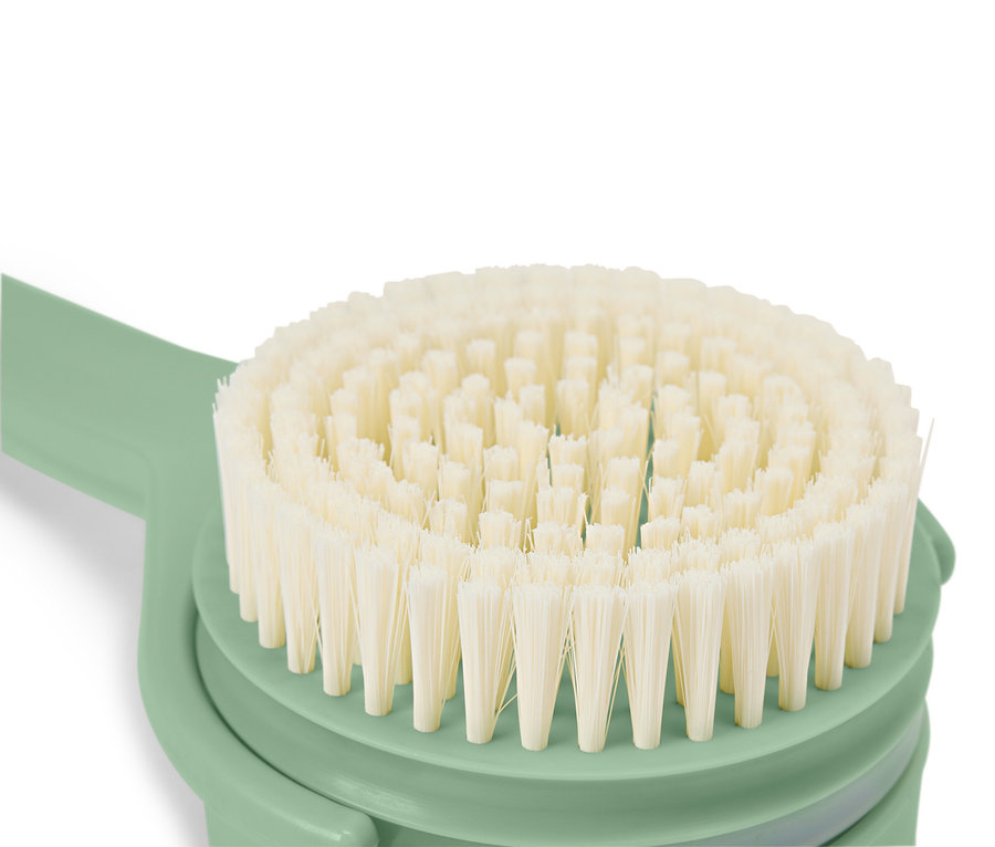 Gros plan d'une brosse ronde avec des poils clairs et un manche vert menthe.