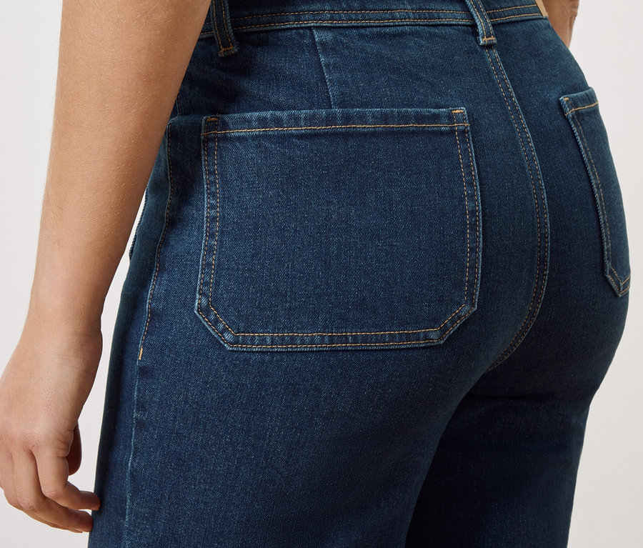 Gros plan du dos d'une personne portant un jean bleu foncé avec des poches arrière plaquées.