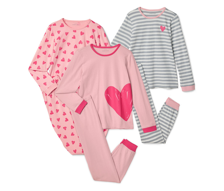 Trois pyjamas pour enfants sont présentés sur un fond blanc. Un pyjama est rose avec des cœurs rouges, un pyjama est rose avec un grand cœur rouge et un pyjama est rayé gris et blanc avec un petit cœur rouge.