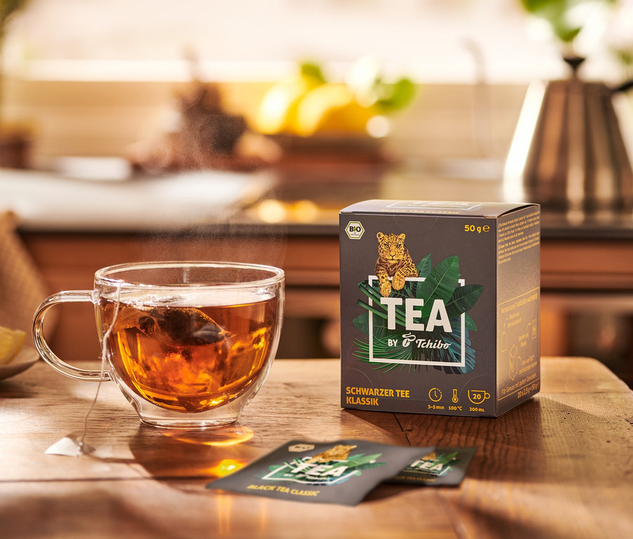 Une tasse de thé à côté d'un paquet de BIO TEA by Tchibo Classique 8x20x2,5g.