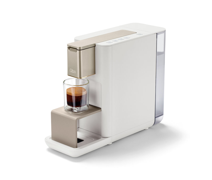Machine à café Qbo ICONIC Light Gold avec une tasse d'espresso.
