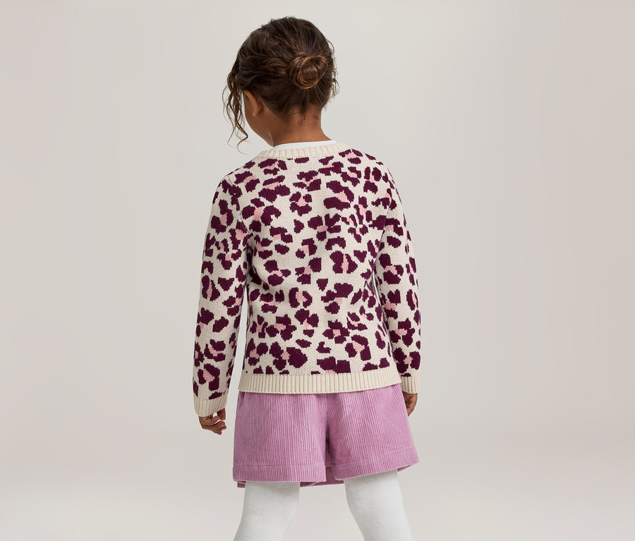 Une jeune fille vue de dos, portant un cardigan crème à imprimé léopard violet, un short en velours côtelé violet et des collants blancs. Ses cheveux foncés sont attachés en chignon.