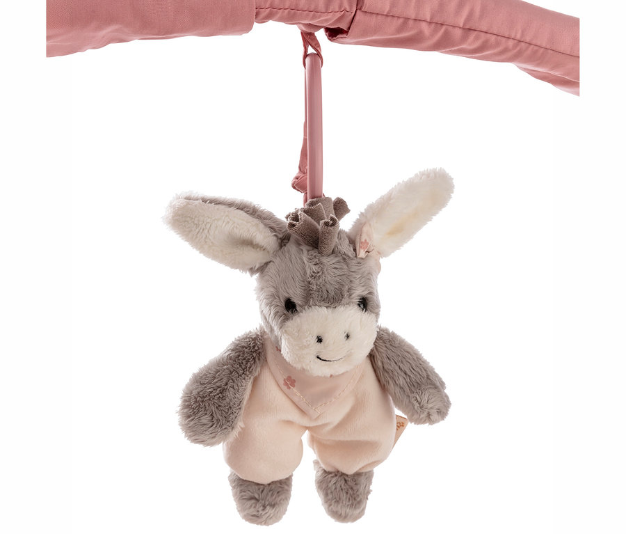 Un jouet âne en peluche gris et blanc est suspendu à une barre rose. L'âne porte une tenue rose clair avec un bavoir.
