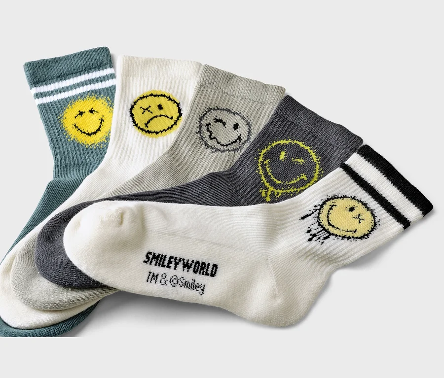 Cinq chaussettes vertes, blanches, grises et anthracite avec des motifs Smileyworld sont superposées.