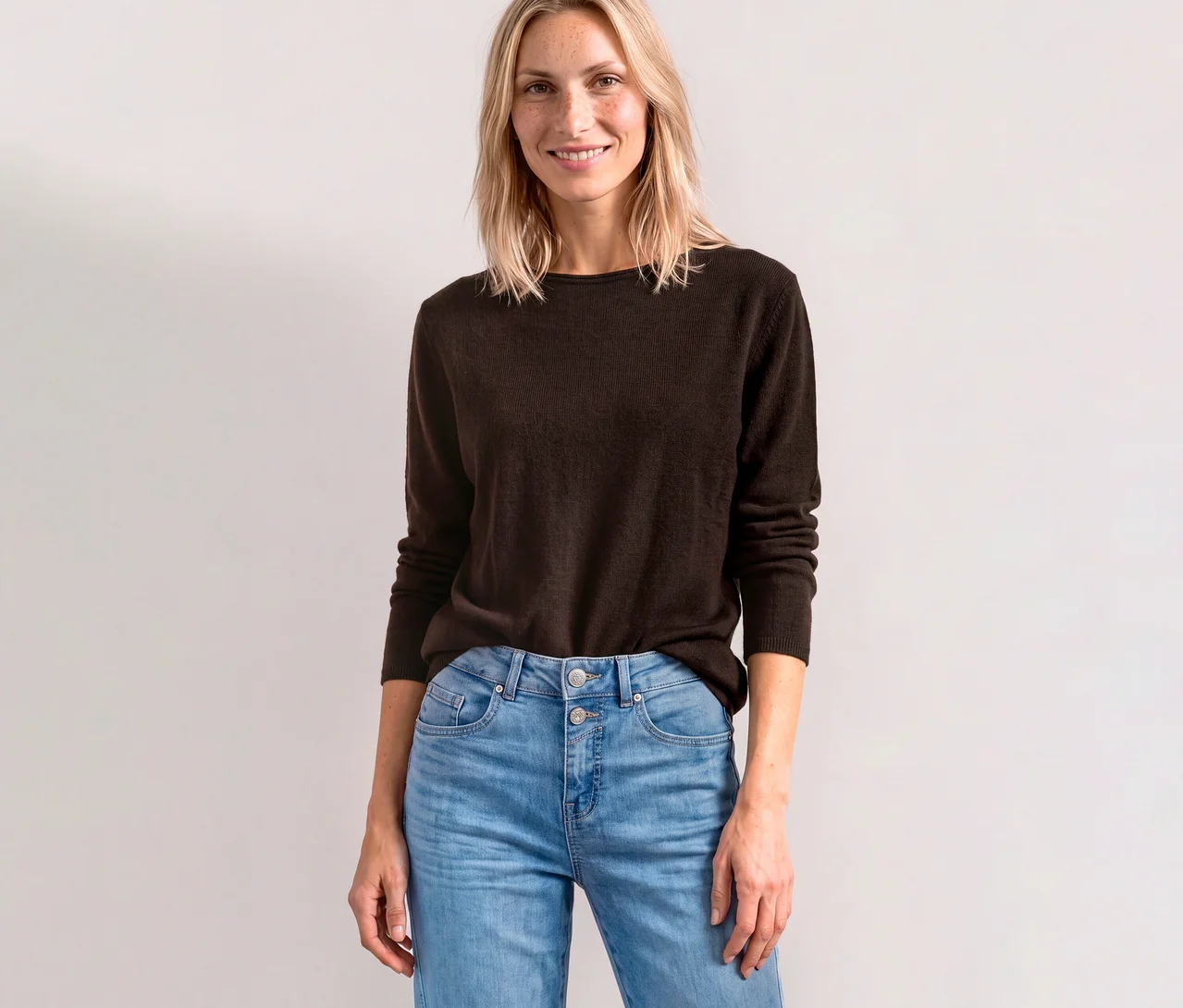 Femme souriante portant un pull en maille Street One marron et un jean clair.