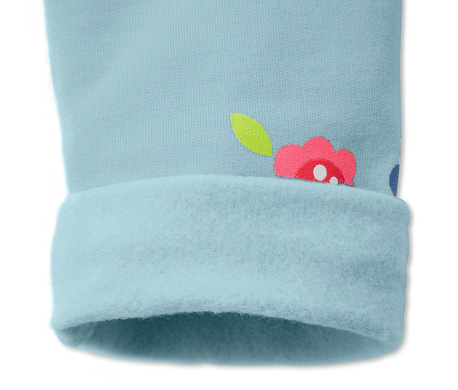 Détail d'un pantalon de survêtement bleu clair avec motif floral et ourlet retroussé.