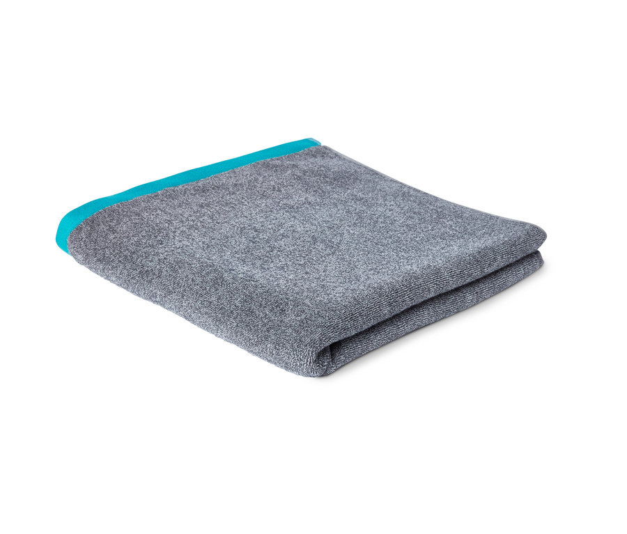 Serviette de bain grise pliée avec une bordure turquoise.