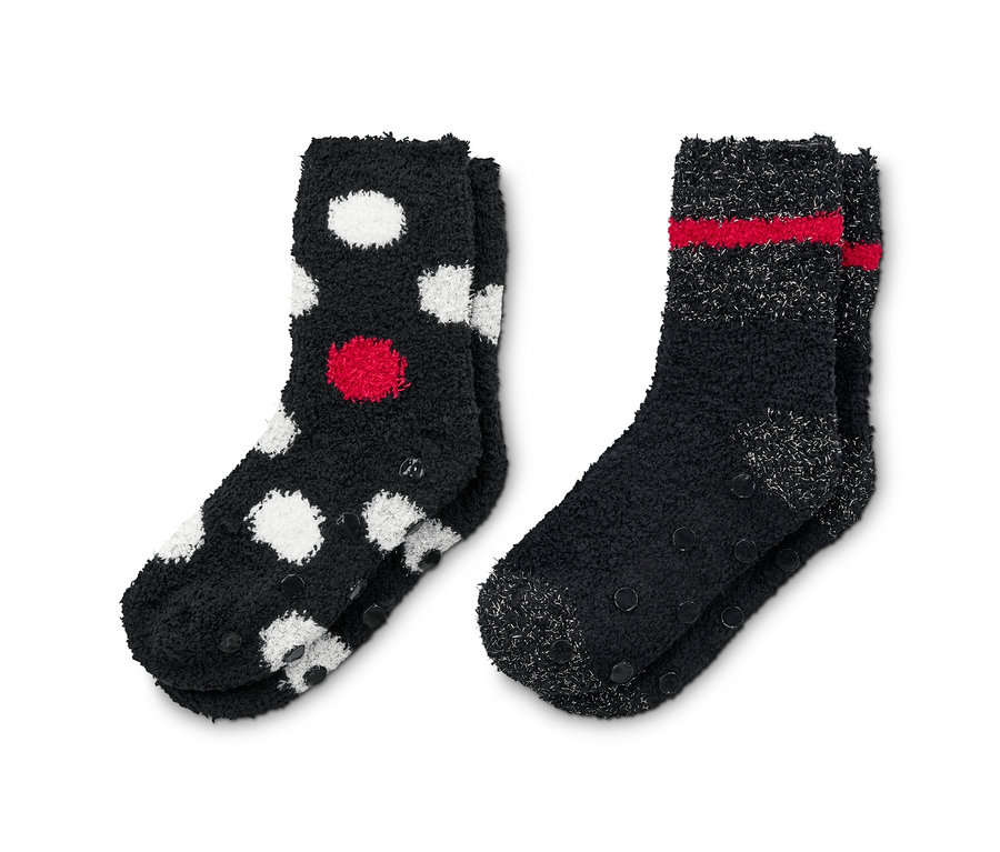 Deux paires de chaussettes moelleuses : une paire noire à pois rouges et blancs, l'autre noire à rayures rouges.