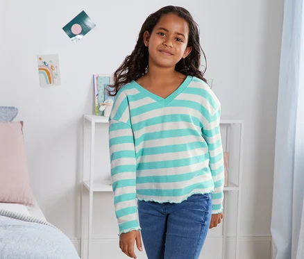 Une fille pose en sweat-shirt rayé bleu en coton bio.