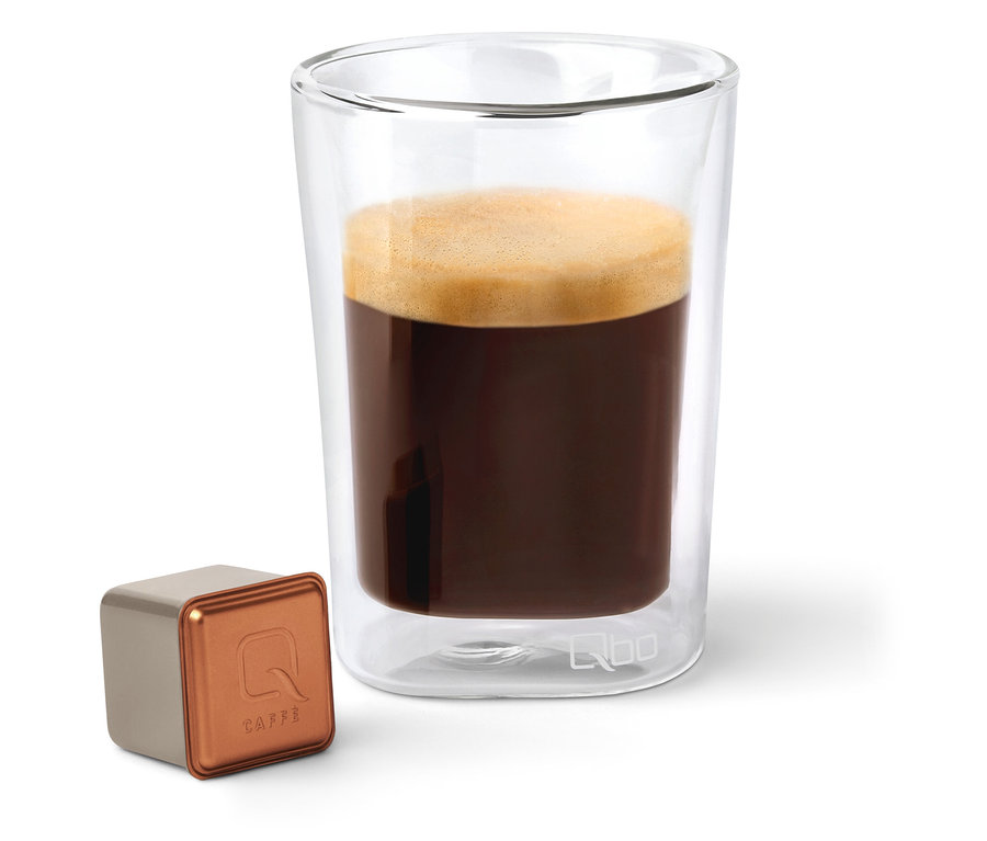 Une capsule de café Qbo Caffè BUNA ENTETA à côté d'un verre de café.