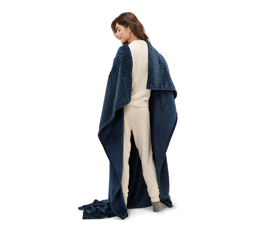 Femme debout, dos tourné, enveloppée dans une couverture moelleuse avec manches intégrées.