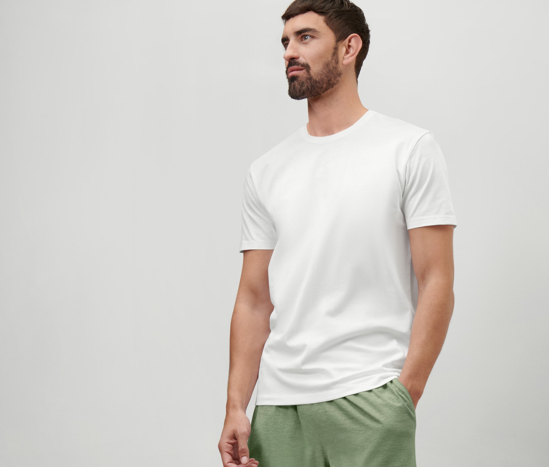 Un homme portant un t-shirt blanc à col rond et un short vert.