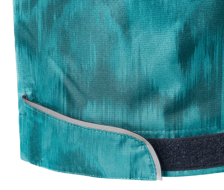 Détail d'un pantalon de pluie imprimé intégral avec des éléments réfléchissants et une fermeture Velcro.