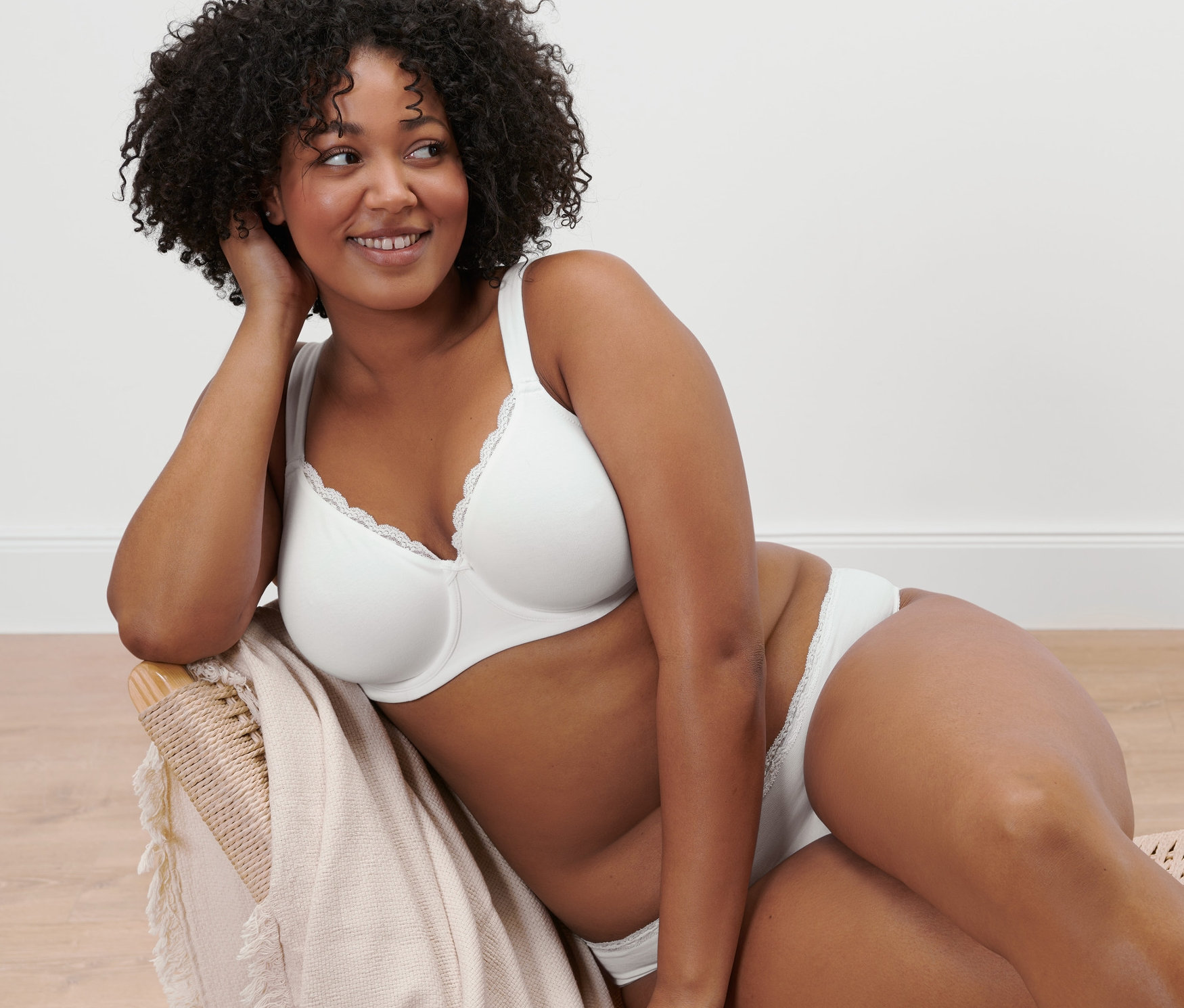 Femme assise sur une chaise portant un soutien-gorge à armatures blanc.