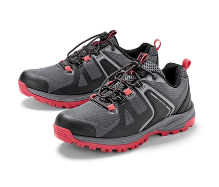 Deux chaussures de trekking grises et noires avec des semelles rouges.