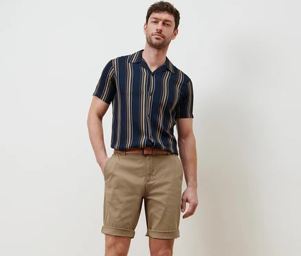 Homme posant en short chino beige.