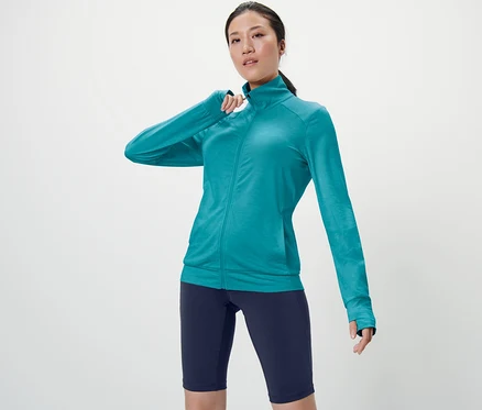 Femme posant en veste fonctionnelle turquoise.