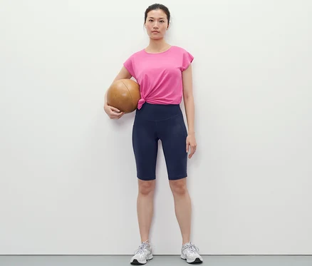 Femme tenant un ballon de basket et portant un cycliste de sport bleu foncé.