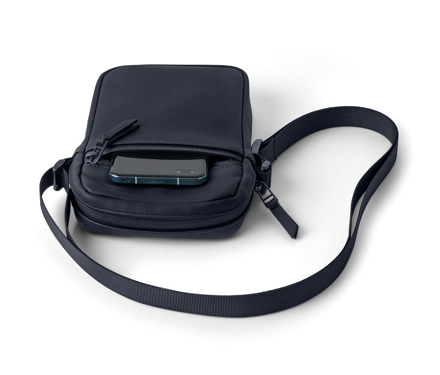 Un sac à bandoulière de pluie bleu marine avec un téléphone dans la poche.