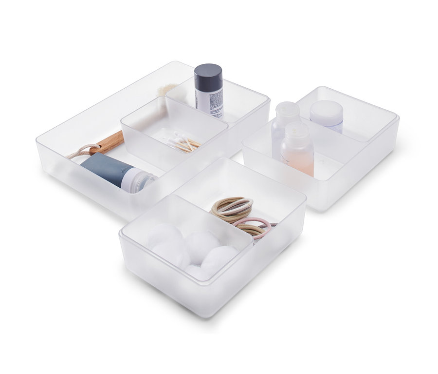 Un set de rangement pour tiroir contenant des boules de coton, des élastiques à cheveux, des cotons-tiges, des bouteilles et une brosse.