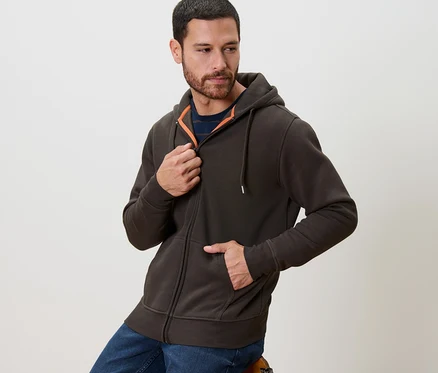 Un homme ferme une veste à capuche marron.