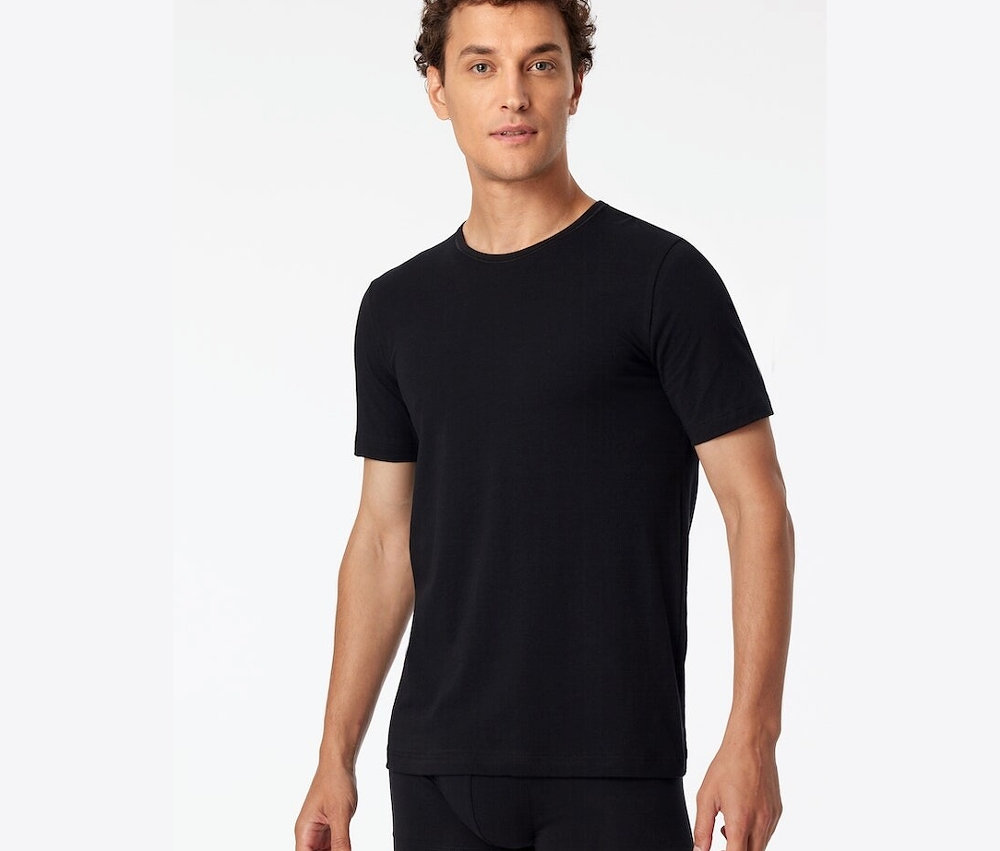 Un homme porte un ensemble de 2 t-shirts SCHIESSER en coton bio, noir.