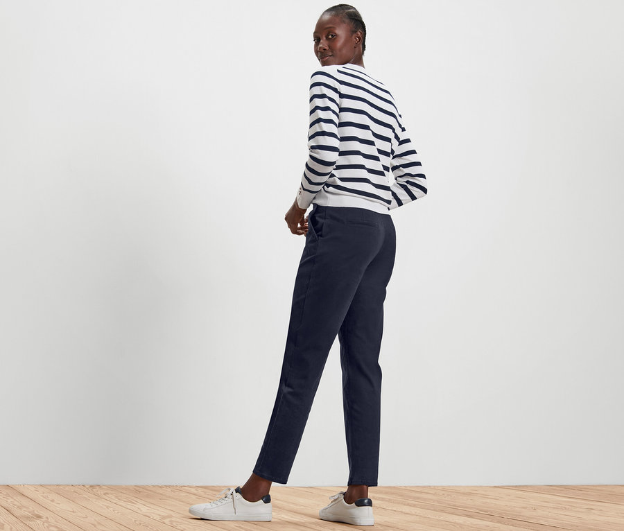 Femme posant en pantalon chino bleu foncé et pull rayé.
