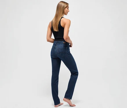Une femme se tient dos à la caméra et porte un jean Angels « Cici » coupe étroite bleu foncé et un débardeur noir.