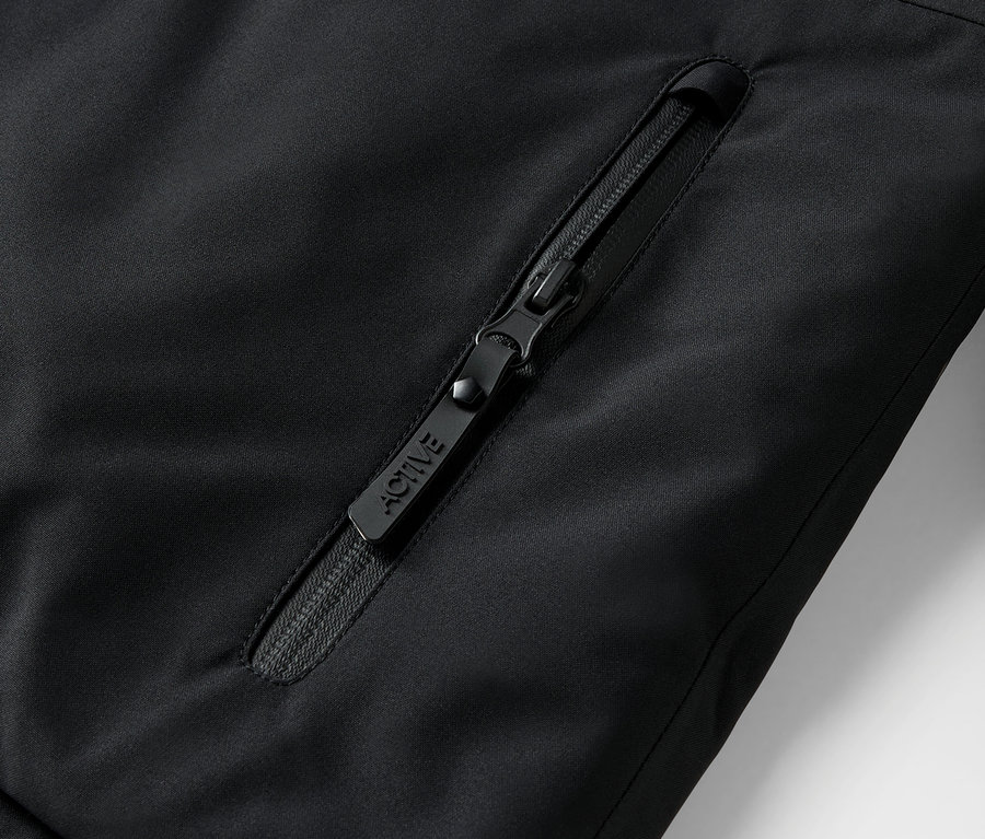 Gros plan d'une fermeture éclair noire sur une veste avec l'inscription ACTIVE.