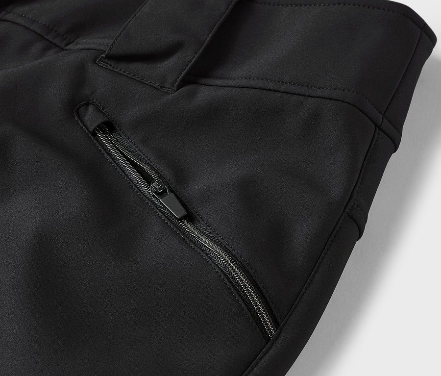 Détail d'un pantalon noir avec une poche zippée.