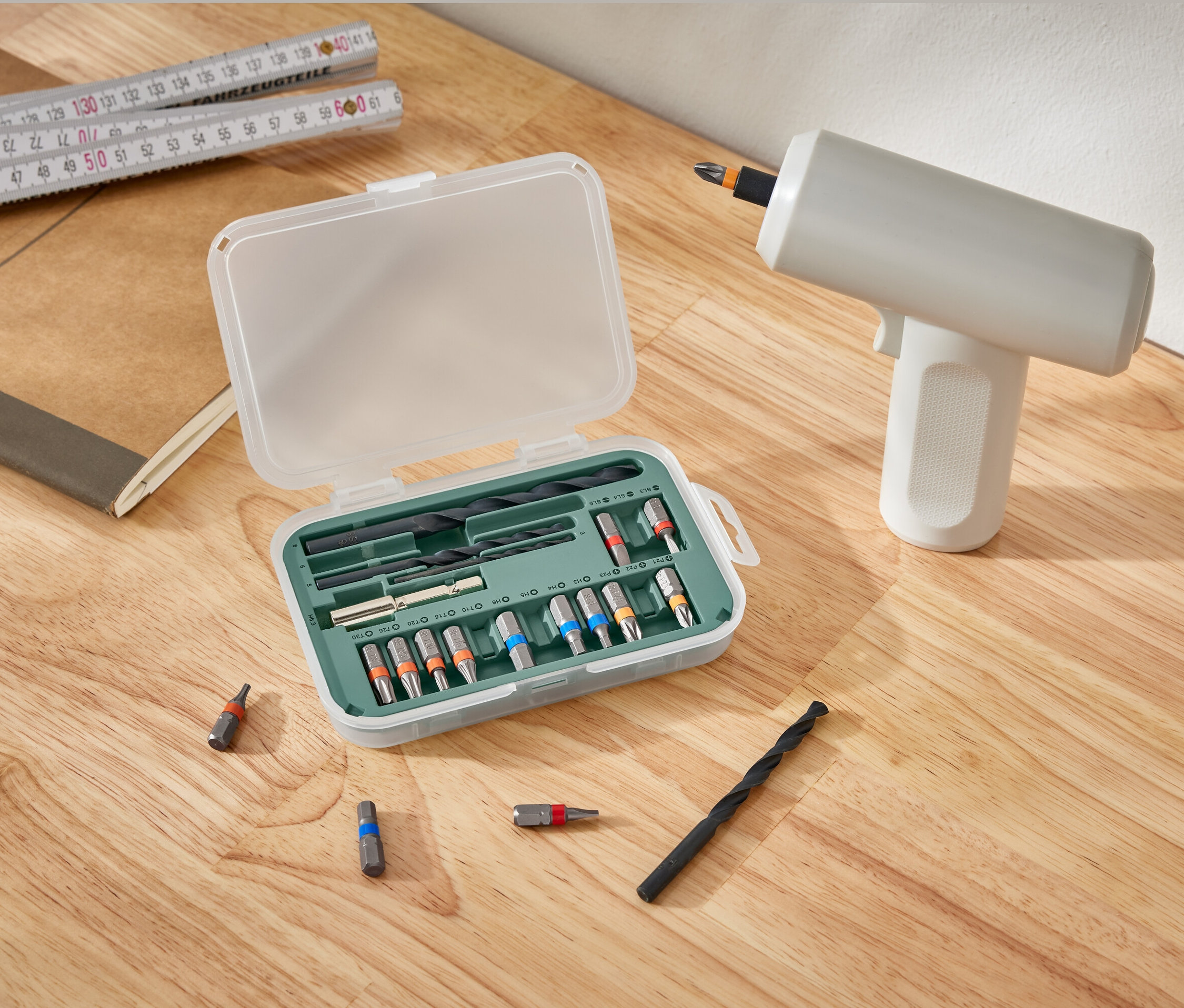 Un kit pour visseuses et perceuses est ouvert à côté d'une perceuse sur une table en bois.