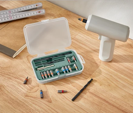 Un kit pour visseuses et perceuses est ouvert à côté d'une perceuse sur une table en bois.