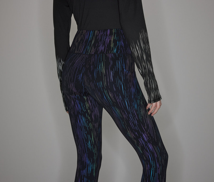 Une personne porte un haut noir à manches longues et un legging brillant.