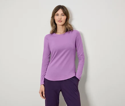 Une femme porte un T-shirt à manches longues violet et un pantalon violet foncé.