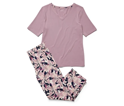 Un t-shirt violet à manches courtes et un pantalon à fleurs reposent sur un fond blanc.