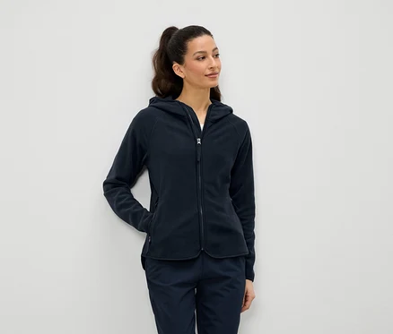 Une femme porte une veste polaire bleu marine à capuche zippée et un pantalon bleu marine.