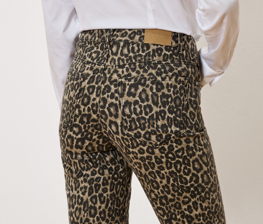 Vue arrière d'une personne portant un pantalon à motif léopard et une chemise blanche.