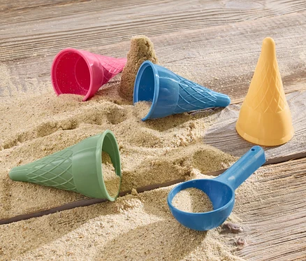 Des moules à glace pour sable et du sable sont posés sur une surface en bois.