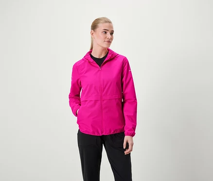 Une femme porte une veste à capuche rose et un pantalon noir.