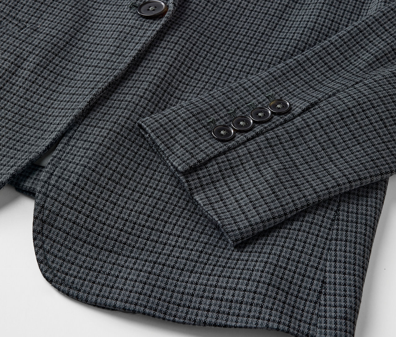 Détail d'un blazer gris avec un motif fin et des boutons sur la manche.